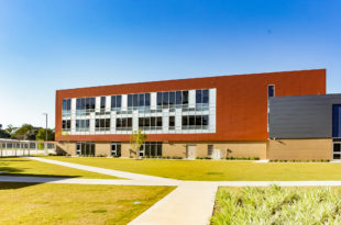 A large school building with orange building panels is pictured.